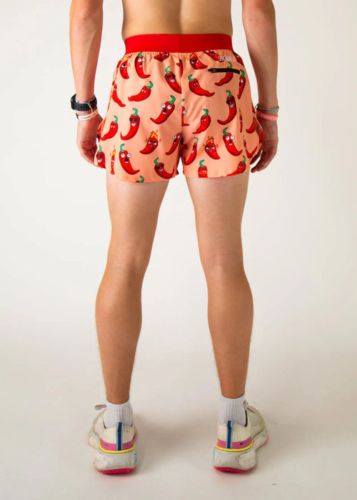 Person wearing a pair of shorts with chili pepper pattern on a plain background