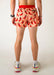 Person wearing a pair of shorts with chili pepper pattern on a plain background