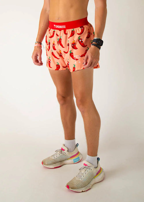 Person wearing a red waistband and pink shorts with chili pepper pattern on a plain background