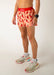 Person wearing a red waistband and pink shorts with chili pepper pattern on a plain background