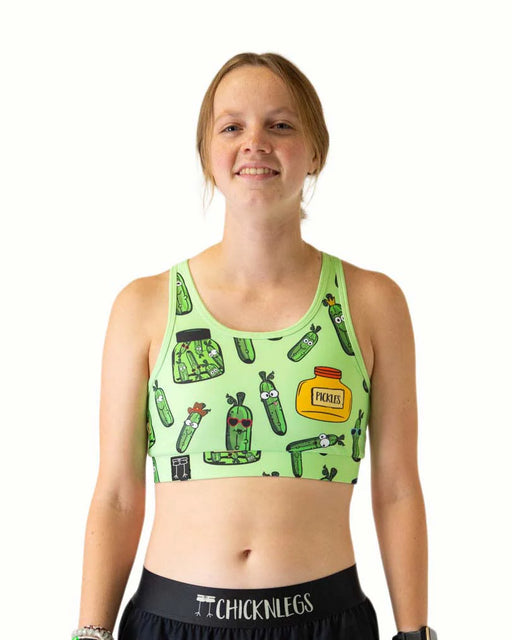 Person wearing a green sports bra with pickle design on a white background