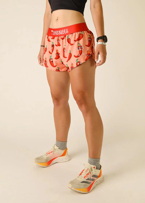 Person wearing pink shorts with chili pepper pattern and red waistband on a beige background