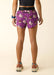 Person wearing purple shorts with cartoon character pattern on a beige background