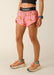 Person wearing pink shorts with banana print and black waistband on a beige background