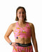 Person wearing a pink sports bra and shorts with banana pattern, holding a black belt.