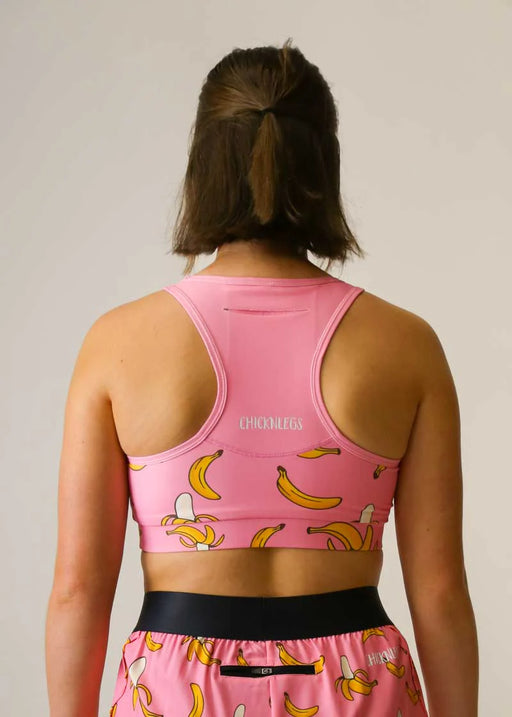 Person wearing a pink sports bra and shorts with banana print on a plain background