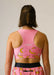 Person wearing a pink sports bra and shorts with banana print on a plain background
