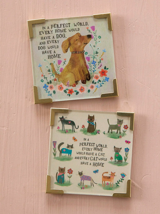 Two framed prints with dog and cat illustrations and text on a pink wall.
