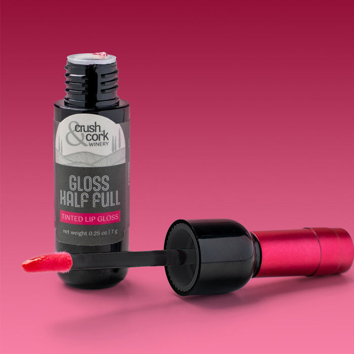 Lip gloss bottle with applicator on a pink background