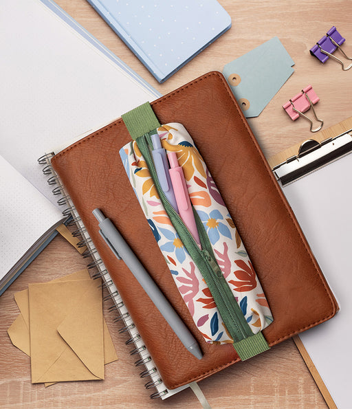 Brown notebook with floral pen holder and stationery items on a wooden desk