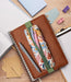 Brown notebook with floral pen holder and stationery items on a wooden desk