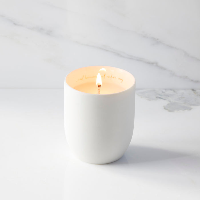 White candle in a ceramic holder on a marble surface
