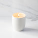 White candle in a ceramic holder on a marble surface