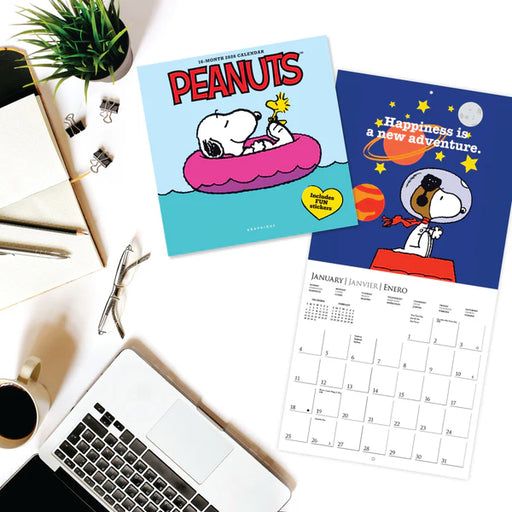 Two Peanuts-themed calendars on a desk with a laptop and coffee cup.