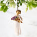 Decorative figurine of a person holding a basket of fruit under hanging greenery on a light background