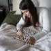 Woman writing in a notebook on a bed with a cozy blanket
