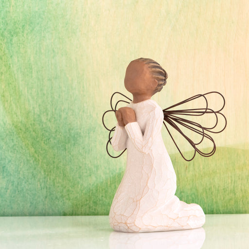 Angel figurine with outstretched wings against a green and beige gradient background