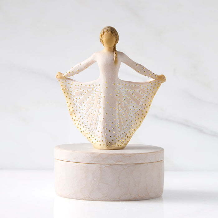 Decorative figurine of a woman with a gold-patterned shawl on a white background