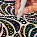Hand holding a marker over a colorful polka dot pattern