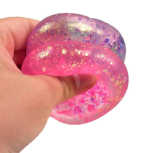 Hand holding a pink and purple glittery stress ball against a white background