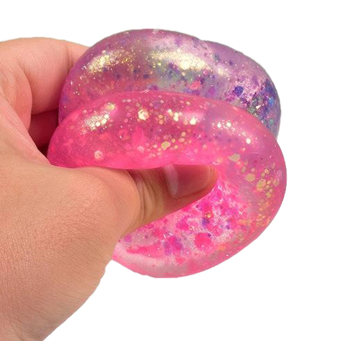 Hand holding a pink and purple glittery stress ball against a white background