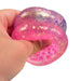 Hand holding a pink and purple glittery stress ball against a white background
