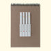 Set of white markers with colored dots on a brown notebook