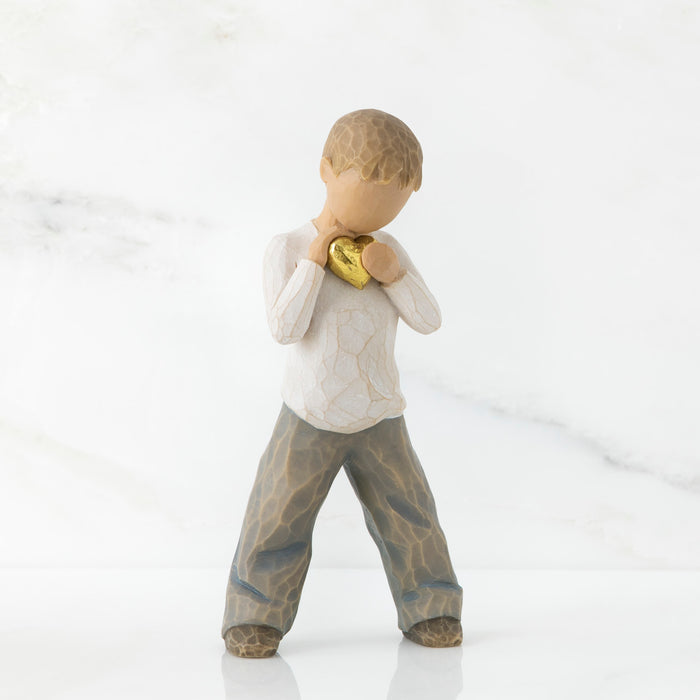 Figurine of a boy holding a gold heart on a white background