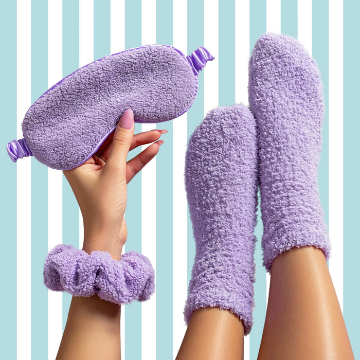 Purple fuzzy eye mask, wristband, and socks held by a hand against a striped background