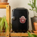 Black mini refrigerator with Smokey Bear logo on a wooden shelf with plants