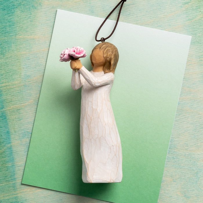 Wooden angel figurine holding flowers on a green card with a textured background