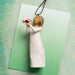 Wooden angel figurine holding flowers on a green card with a textured background