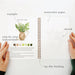 Open notebook with watercolor paper, sketch, and step-by-step instructions on a white background