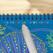 Colorful dot pattern on a blue notebook with a pen on a wooden surface