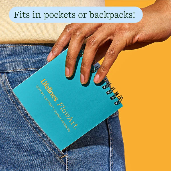 Person placing a teal notebook with 'Lifelines FlowArt' branding into a pocket against an orange background.