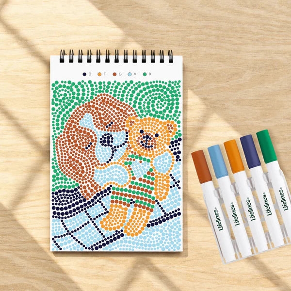 Coloring book with a bear design and markers on a wooden surface