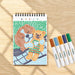 Coloring book with a bear design and markers on a wooden surface