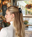 Woman with a coffin-shaped hair clip in her hair, standing in a decorated outdoor setting.