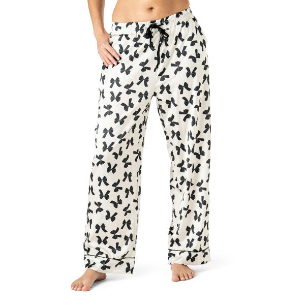 White pajama pants with black bow 
pattern worn by a person on a white background