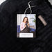 Black knit blanket with a tag featuring a woman holding a baby, branded 'hello mello'.