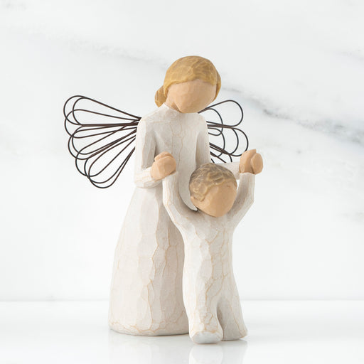 Decorative figurine of an angel holding a child on a white background