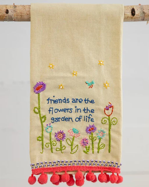 Embroidered towel with floral designs and text on a wooden stick against a light background