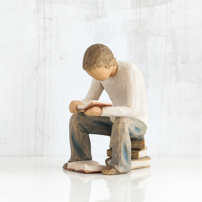 Statue of a person sitting and reading a book on a white background