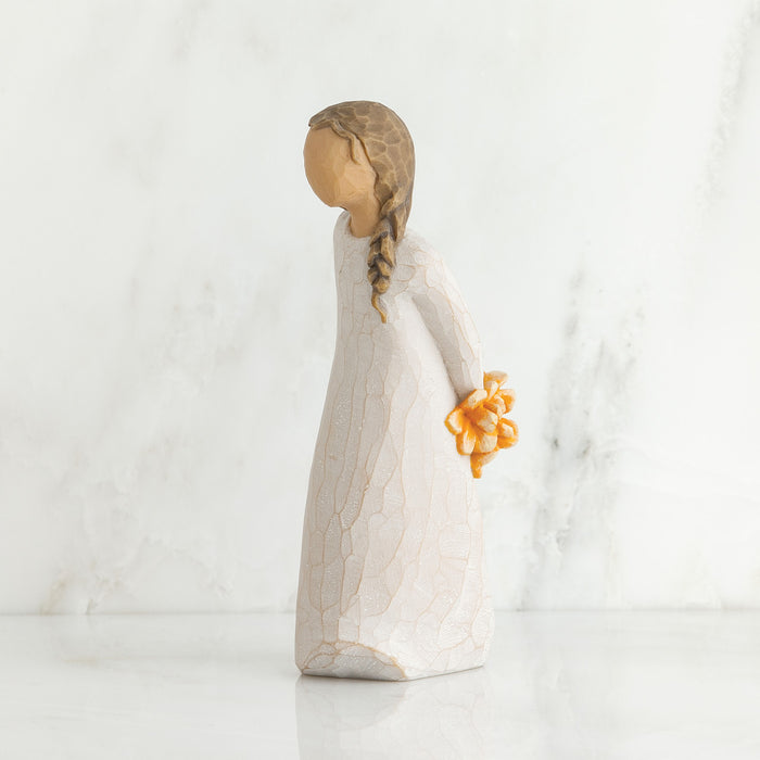 Decorative figurine of a woman holding a flower on a white marble surface