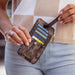 Camouflage-patterned wallet with visible brand name held by a person wearing a checkered shirt.
