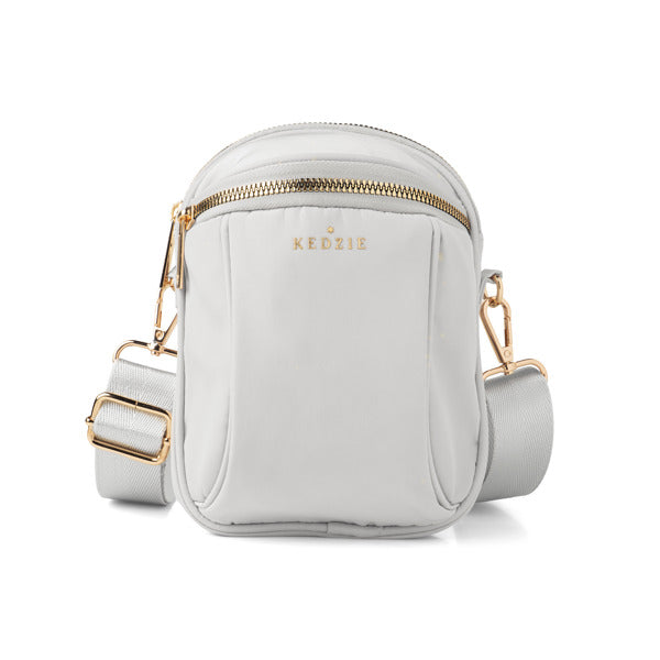 White crossbody bag with gold accents on a white background