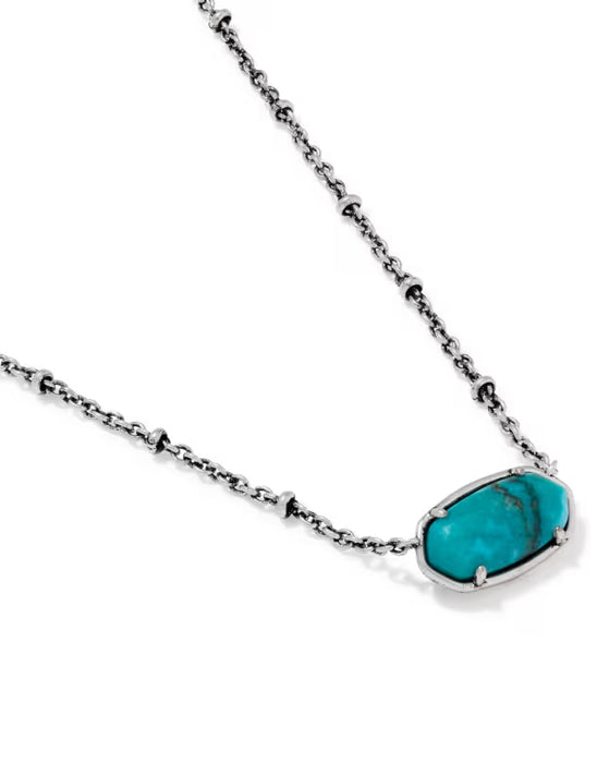 A silver-toned necklace featuring a textured, bezel-set turquoise stone pendant on a clean white background.