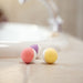 Three colorful bath bombs on a bathroom counter with a blurred background