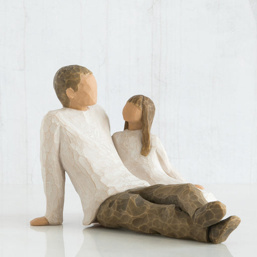 Wooden figurine of a man and woman sitting together on a white background