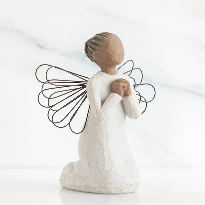 Figure of angel with darker skin tone and hair color, in cream dress and wire wings, kneeling with hands in prayer position